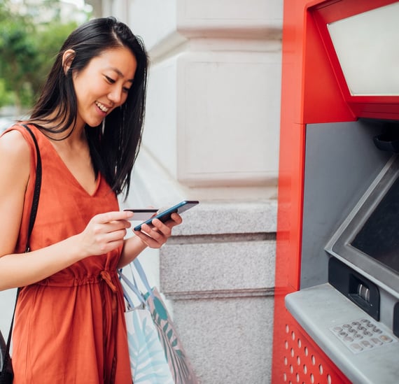 woman using ATM successfully accesses all her financial and banking information through mobile app